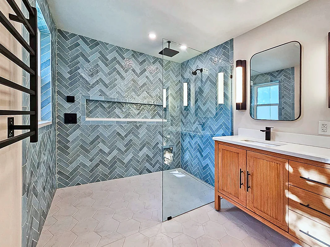 Villanova bathroom with blue herringbone shower tile and wood vanity remodeled by dRemodeling.