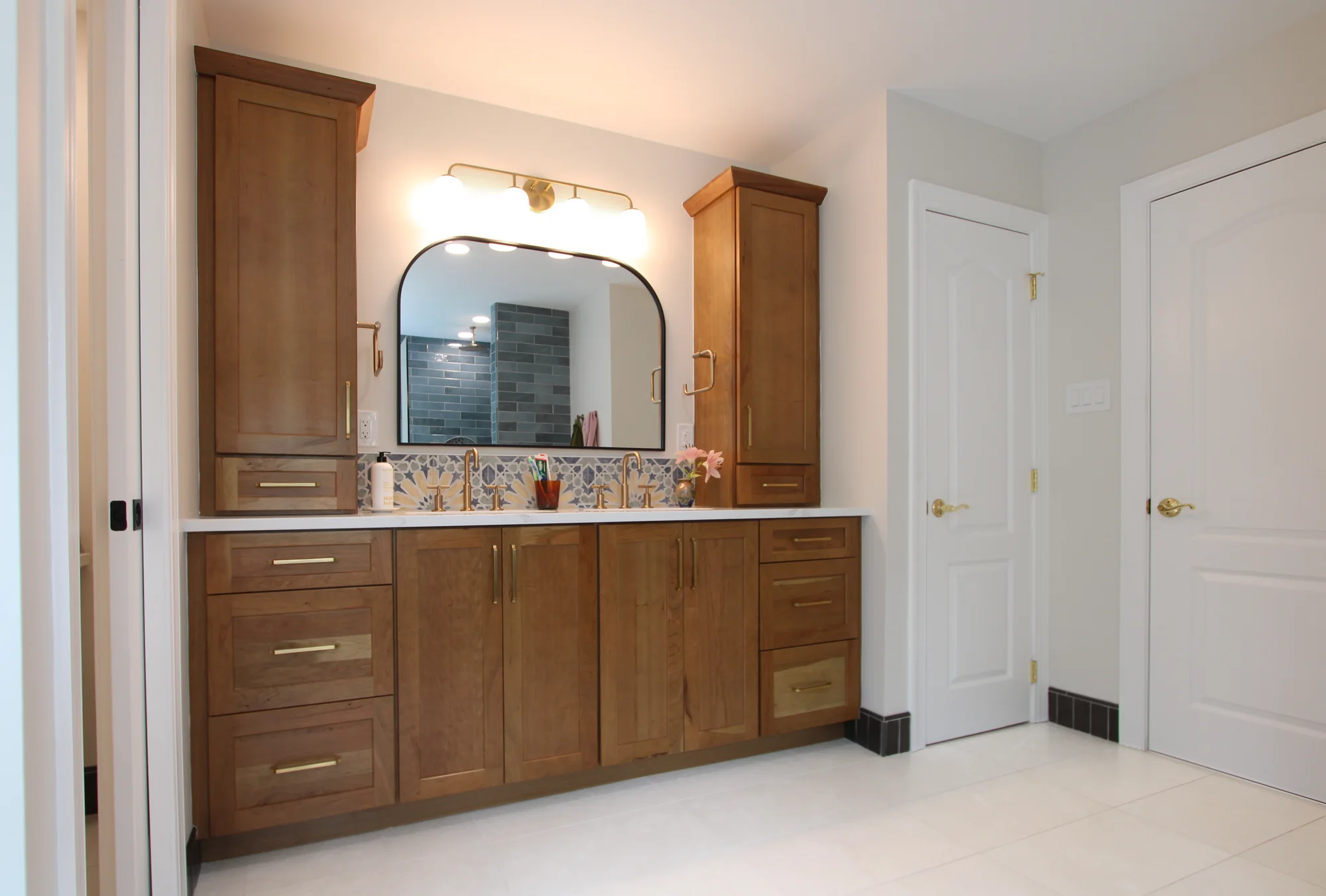 Doylestown primary bathroom double vanity with cherry cabinetry, floral backsplash and brass fixtures